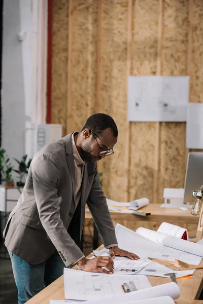 Bonito arquiteto afro-americano desenhando planos arquitetônicos no local de trabalho — Fotografia de Stock