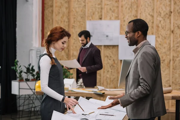 Equipo de arquitectos hablando y trabajando juntos en la oficina moderna - foto de stock