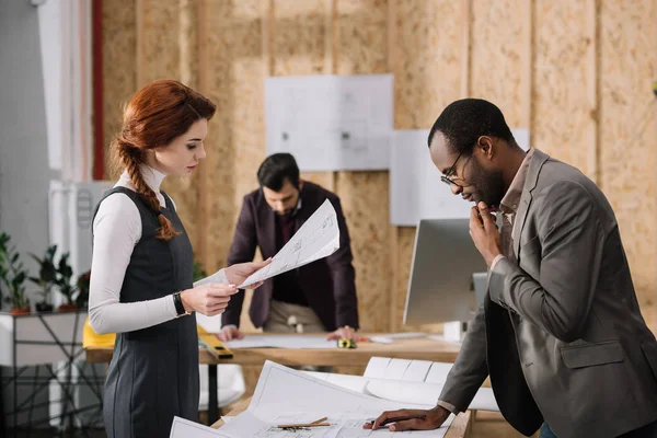 Équipe ciblée d'architectes travaillant ensemble dans un bureau moderne — Photo de stock