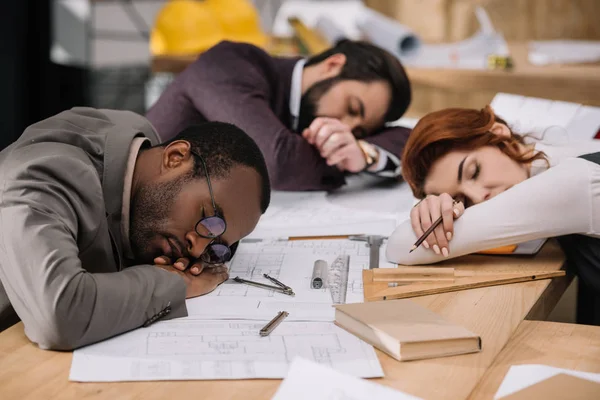 Überarbeitetes multiethnisches Architektenteam schläft im Büro — Stockfoto
