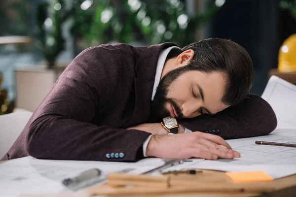 Exhausted architect sleeping on building plans at workplace — Stock Photo