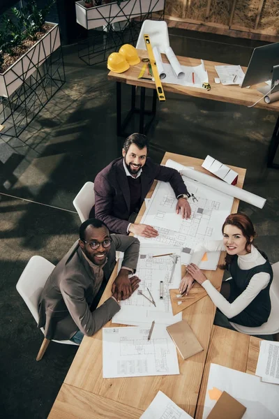 Aus der Vogelperspektive: Architektenteam mit Architekturplänen sitzt zusammen im Konferenzsaal — Stockfoto