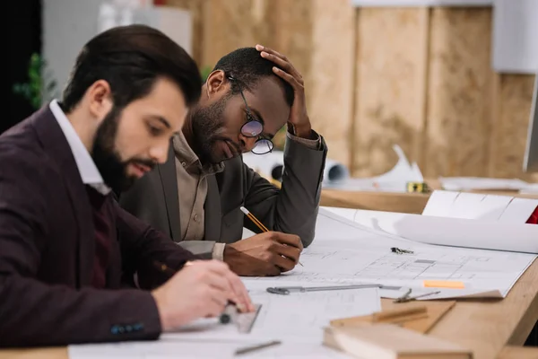 Jeunes architectes concentrés dessinant ensemble des plans architecturaux — Photo de stock