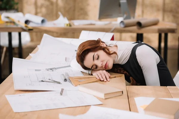 Architecte femme surmenée dormir sur les plans de construction sur le lieu de travail — Photo de stock