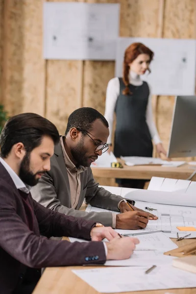 Equipo concentrado de arquitectos trabajando juntos en una oficina moderna - foto de stock