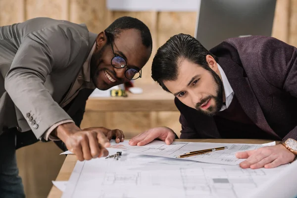 Young multiethnic architects discussing building plans — Stock Photo