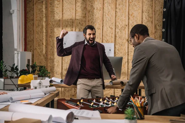 Jeunes architectes jouant au baby-foot au bureau — Photo de stock