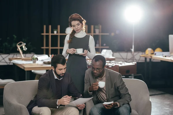 Jóvenes empresarios multiétnicos trabajando juntos y tomando café - foto de stock