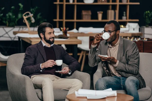 Empresários bem sucedidos sentados em poltronas com café — Fotografia de Stock