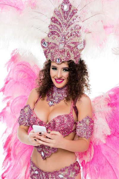 Woman in carnival costume using smartphone while looking at camera, isolated on white — Stock Photo