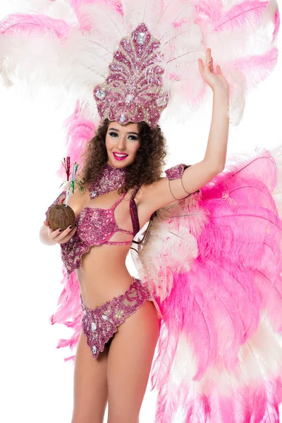 Mujer en traje de carnaval sosteniendo coco con pajitas y mirando a la cámara con la mano levantada, aislado en blanco - foto de stock