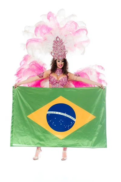 Happy young woman in carnival costume with pink feathers holds large flag of Brasil isolated on white — Stock Photo