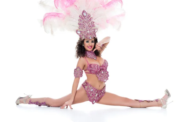 Mujer joven feliz en traje de carnaval con plumas de color rosa realiza split aislado en blanco - foto de stock