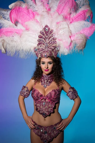 Mujer brillante en traje de carnaval con plumas rosadas aisladas sobre fondo azul - foto de stock
