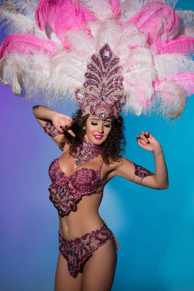Happy young woman in carnival costume with pink feathers on blue background — Stock Photo