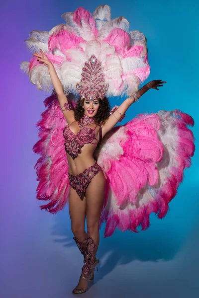 Mulher brilhante em traje de carnaval com penas rosa no fundo azul — Fotografia de Stock