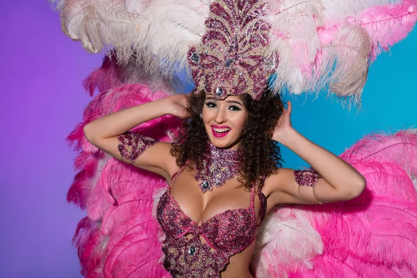 Donna brillante in costume di carnevale con piume rosa ballare e sorridere isolato su sfondo blu — Foto stock