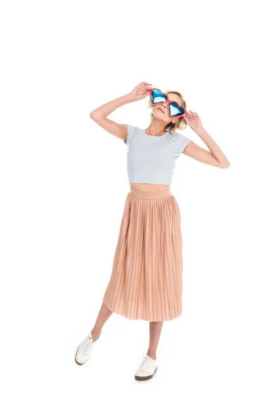 Ganzkörperansicht der schönen jungen Frau in herzförmiger Sonnenbrille posiert isoliert auf weiß — Stockfoto