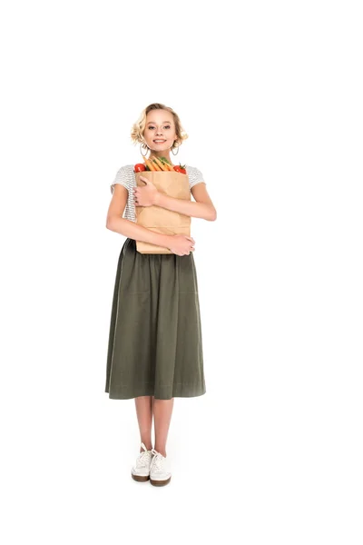 Full length view of beautiful young woman holding grocery bag and looking at camera isolated on white — Stock Photo