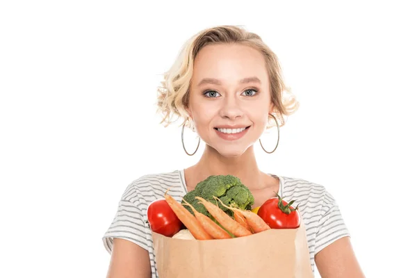 Hermosa mujer joven sosteniendo bolsa de comestibles y mirando a la cámara aislada en blanco - foto de stock