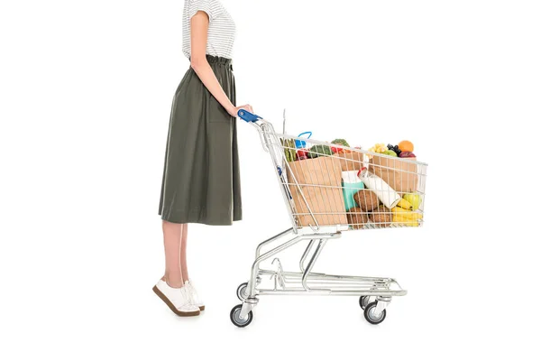 Vista laterale della donna in piedi con carrello della spesa con sacchetti di carta e generi alimentari isolati su bianco — Foto stock