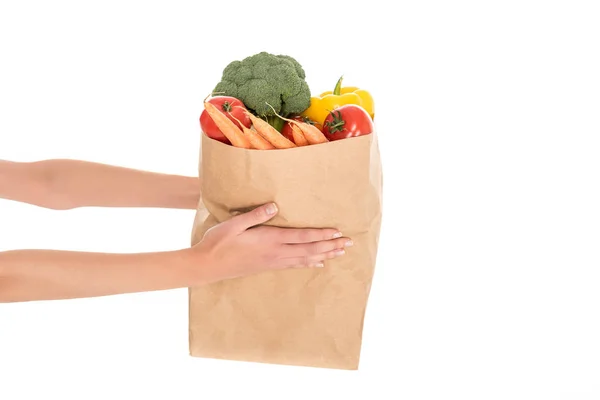 Close-up partial view of woman holding paper bag with fruits and vegetables isolated on white — Stock Photo