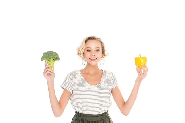 Bela jovem segurando brócolis fresco com pimenta e sorrindo para a câmera isolada no branco — Fotografia de Stock