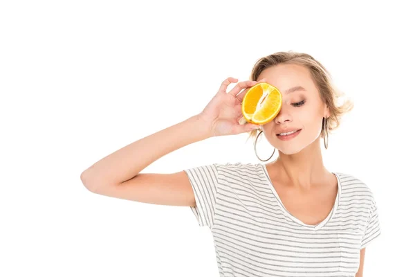 Attraente giovane donna che tiene la metà di arancione vicino al viso isolato su bianco — Foto stock