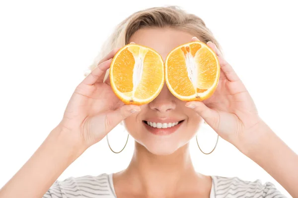 Bela jovem sorridente segurando metades de laranja perto do rosto isolado no branco — Fotografia de Stock