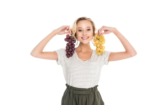 Beautiful young woman holding bunches of grapes and smiling at camera isolated on white — Stock Photo
