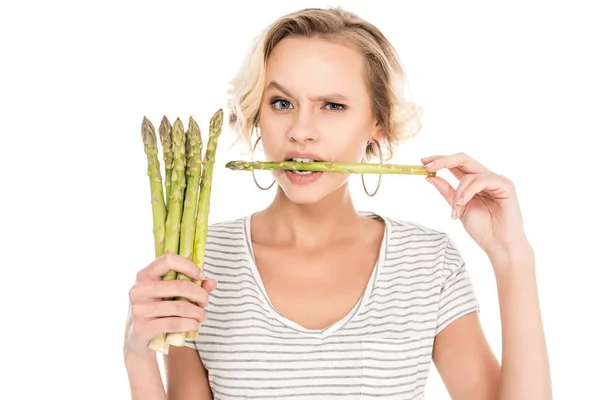 Portrait of young woman biting raw asparagus in hands isolated on white — Stock Photo