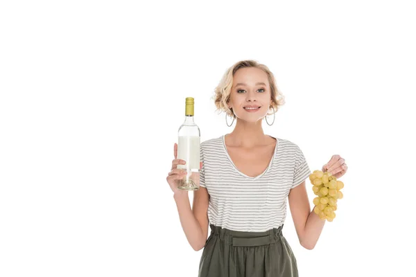 Портрет улыбающейся женщины с бутылкой вина и винограда в руках, изолированных на белом — стоковое фото