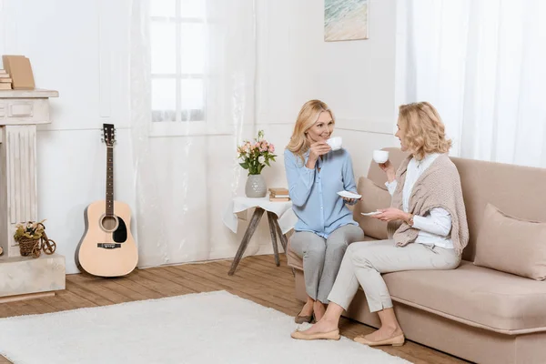 Две женщины среднего возраста сидят на диване и пьют чай — стоковое фото
