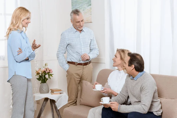 Старші чоловіки і жінки розмовляють під час пиття чаю на дивані — стокове фото
