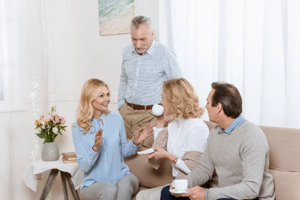 Старшие мужчины и женщины разговаривают за чашкой чая на диване — Stock Photo