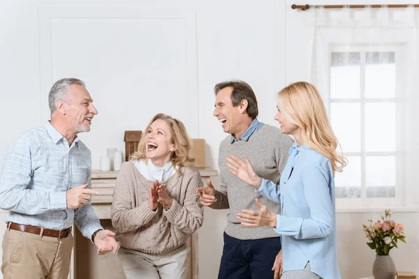 Літні чоловіки і жінки мають дружню розмову і сміються у вітальні — стокове фото