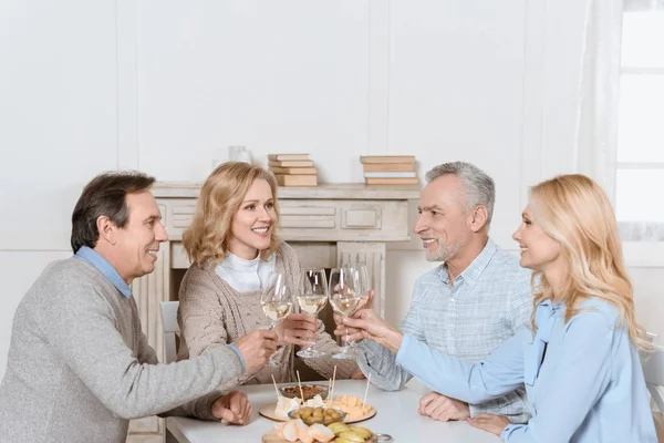 Happy friends cheering while sitting at table in room interior — Stock Photo