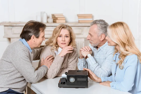 Freunde sitzen am Tisch, während sie einen Projektor auf dem Tisch benutzen — Stockfoto