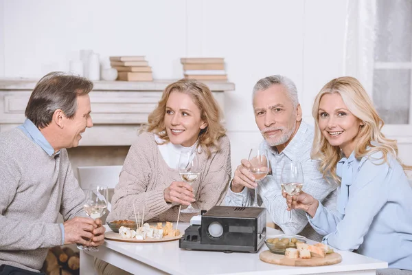 Freunde sitzen mit Essen und Projektor am Tisch im Innenraum — Stockfoto