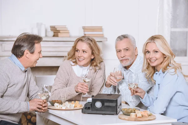 Friends sitting at table with food and projector in room interiorn — Stock Photo