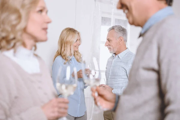 Amigos felices hablando y sosteniendo gafas en las manos en la habitación - foto de stock