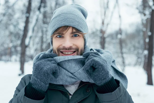 Porträt eines gut aussehenden, lächelnden Mannes, der im Winterpark in die Kamera blickt — Stockfoto