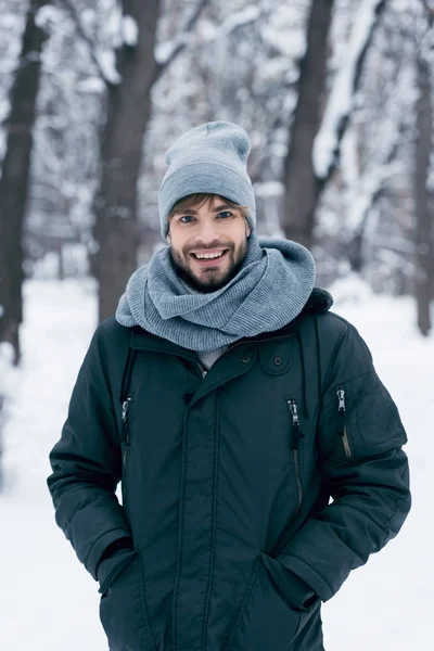 Portrait d'un bel homme souriant regardant une caméra dans un parc d'hiver — Photo de stock