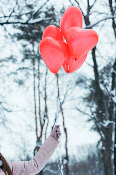 Tiro recortado de mujer sosteniendo globos en forma de corazón en la mano - foto de stock