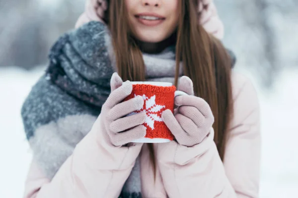 Foco seletivo da mulher com xícara de café quente nas mãos no parque nevado — Fotografia de Stock