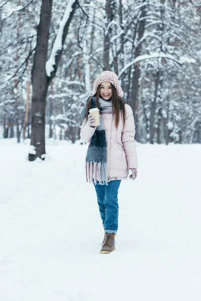 Attractive woman in winter clothing with coffee to go on winter day walking in park — Stock Photo