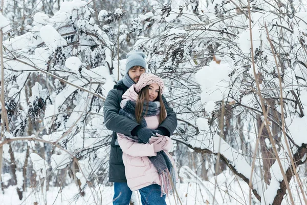 Young man hugging girlfriend in winter forest — Stock Photo