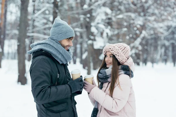 Side view of cheerful couple with coffee to go in snowy park — Stock Photo