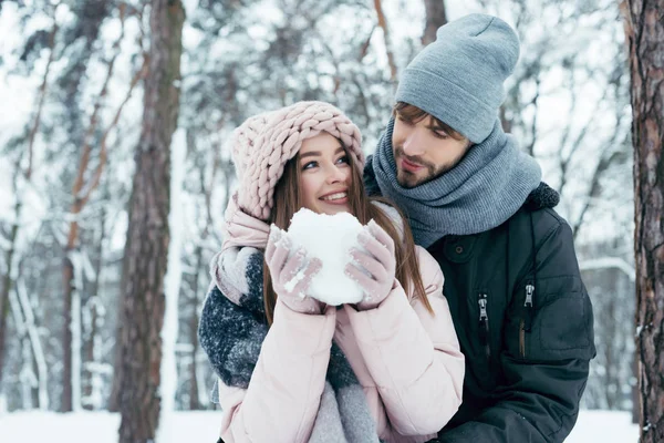 Young couple having fun together in snowy forest — Stock Photo