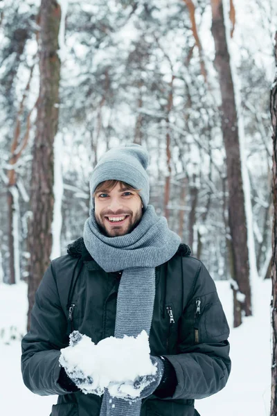 Retrato de un joven feliz jugando con la nieve en el parque de invierno - foto de stock